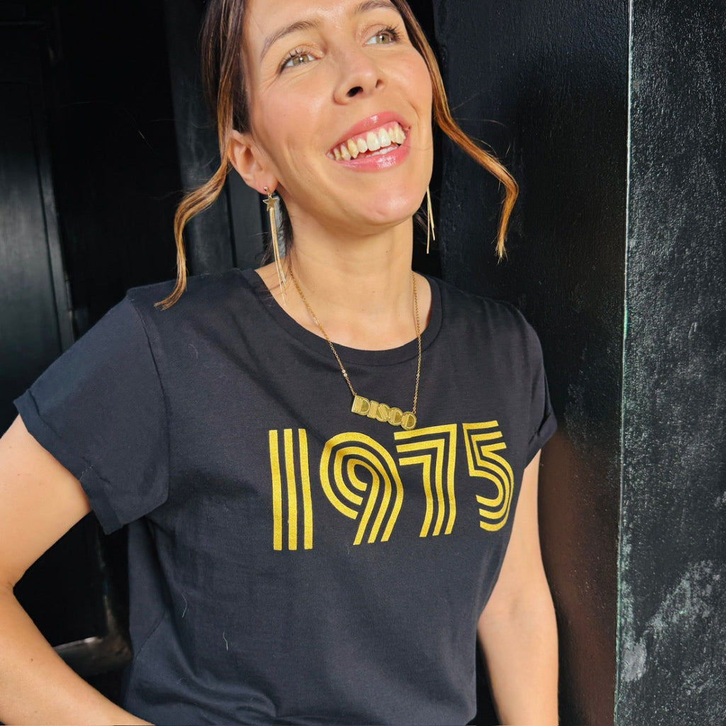 Woman wearing a black t-shirt with '1975' printed in yellow.