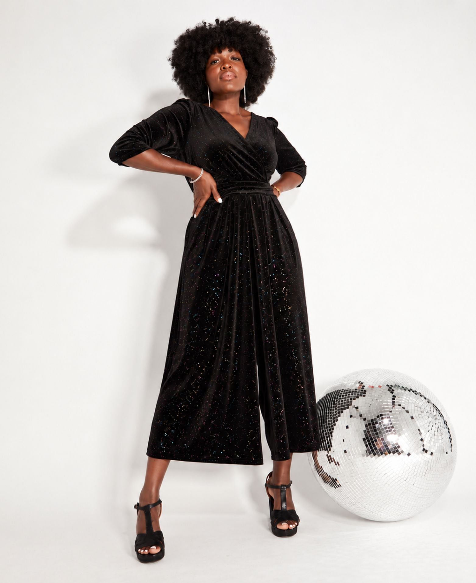 Black Rainbow Sparkle Jumpsuit lower viewpoint with heels and disco ball for party season and new year