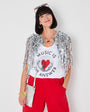 Woman wearing a vest with 'Music is the Answer' text and a red skirt against a wooden background.