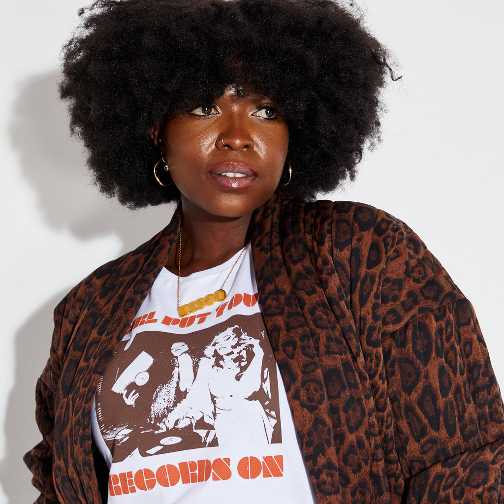 Woman wearing a leopard print coat over a graphic t-shirt with text and images.