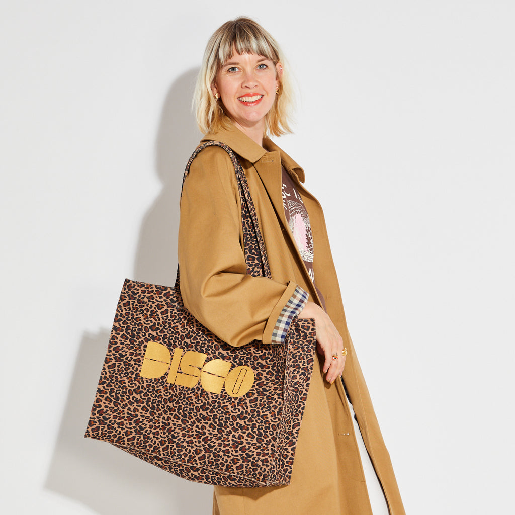 Woman holding a leopard print tote bag with 'DISCO' text on a white background