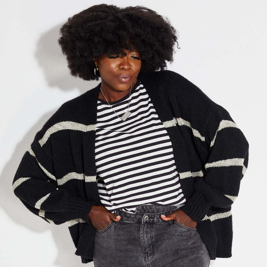 Woman wearing a black and white striped shirt with a black gold metallic stripe cardigan on a white background