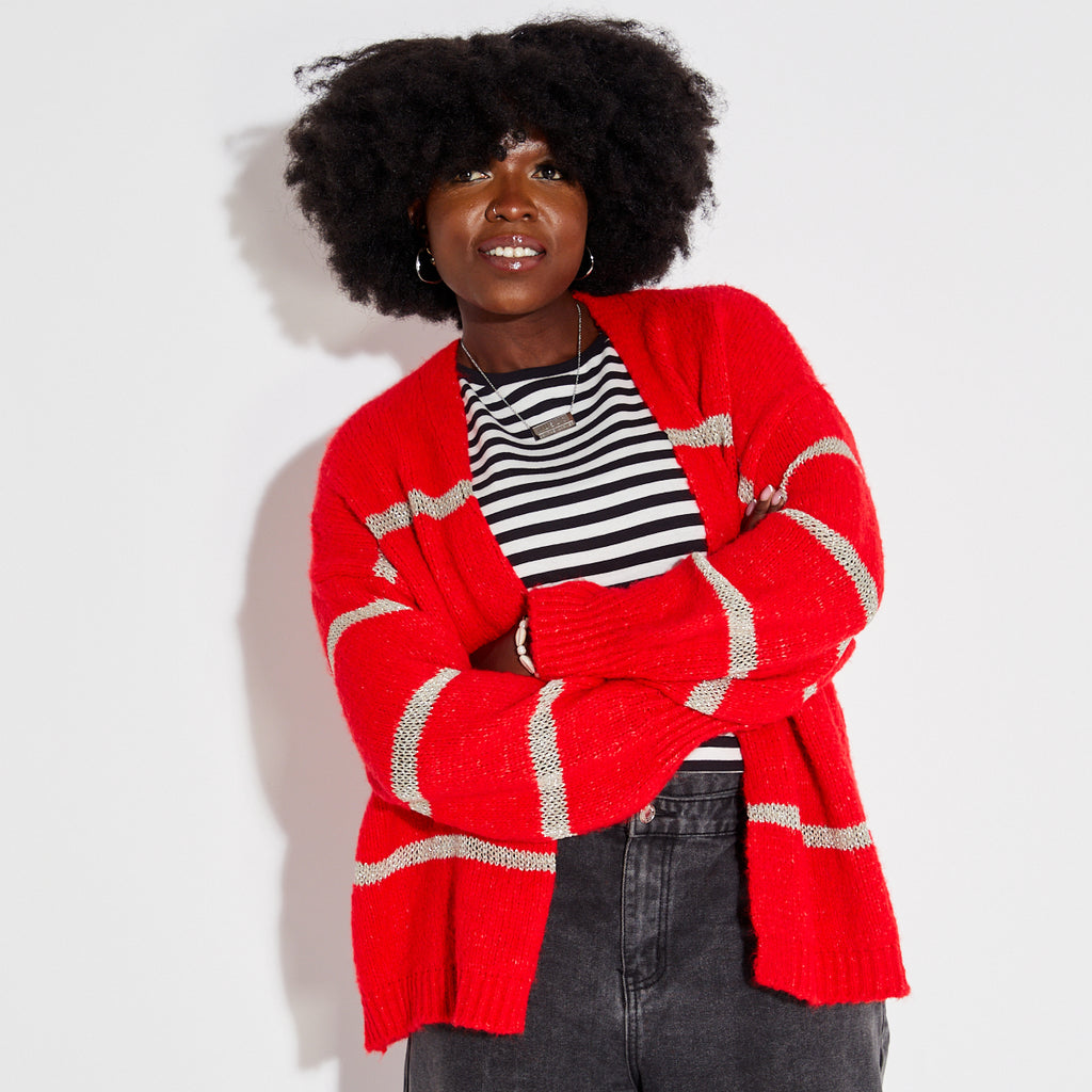 Person wearing a red metallic stripe disco cardigan over a striped shirt on a white background