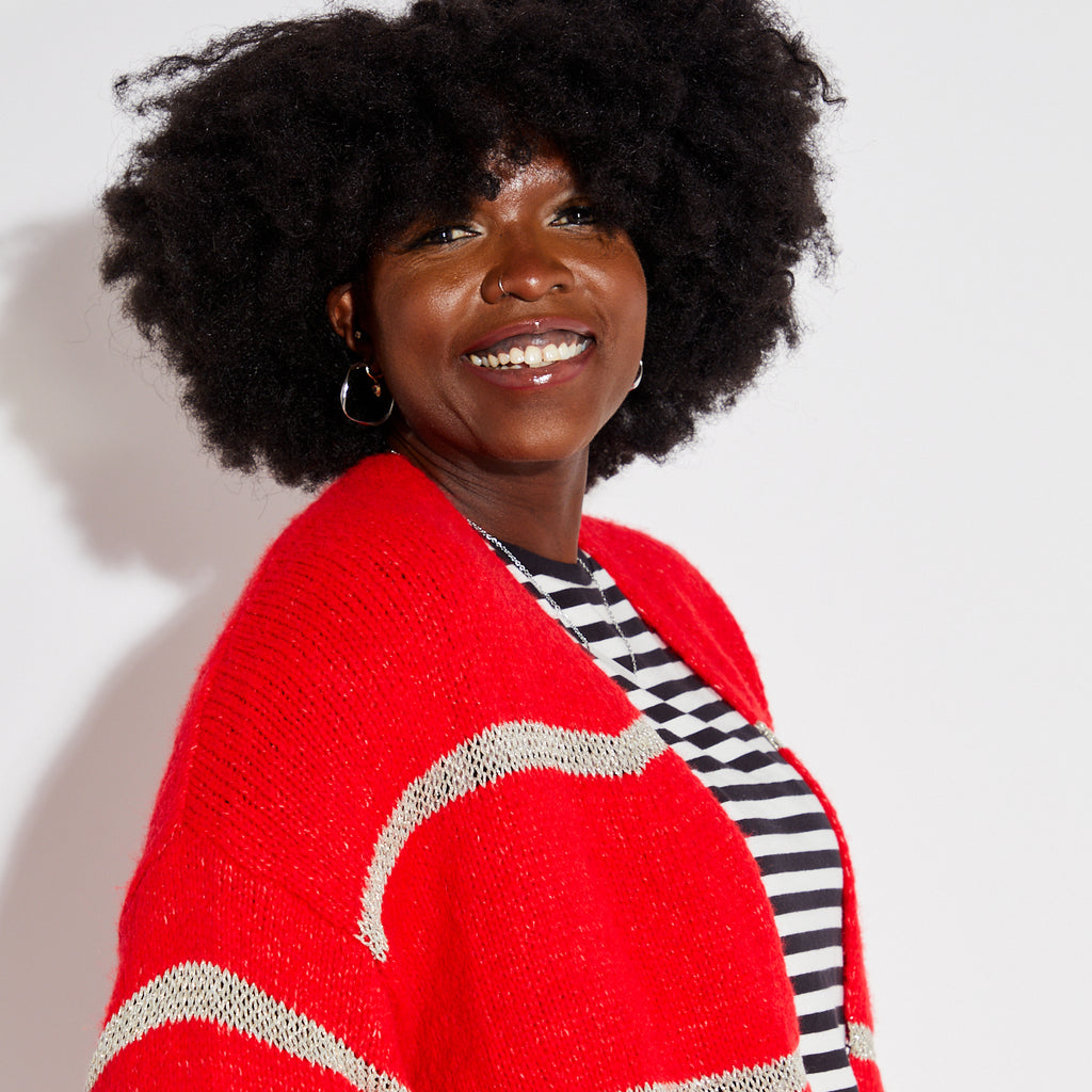 Person wearing a red metallic stripe disco cardigan over a striped shirt on a white background