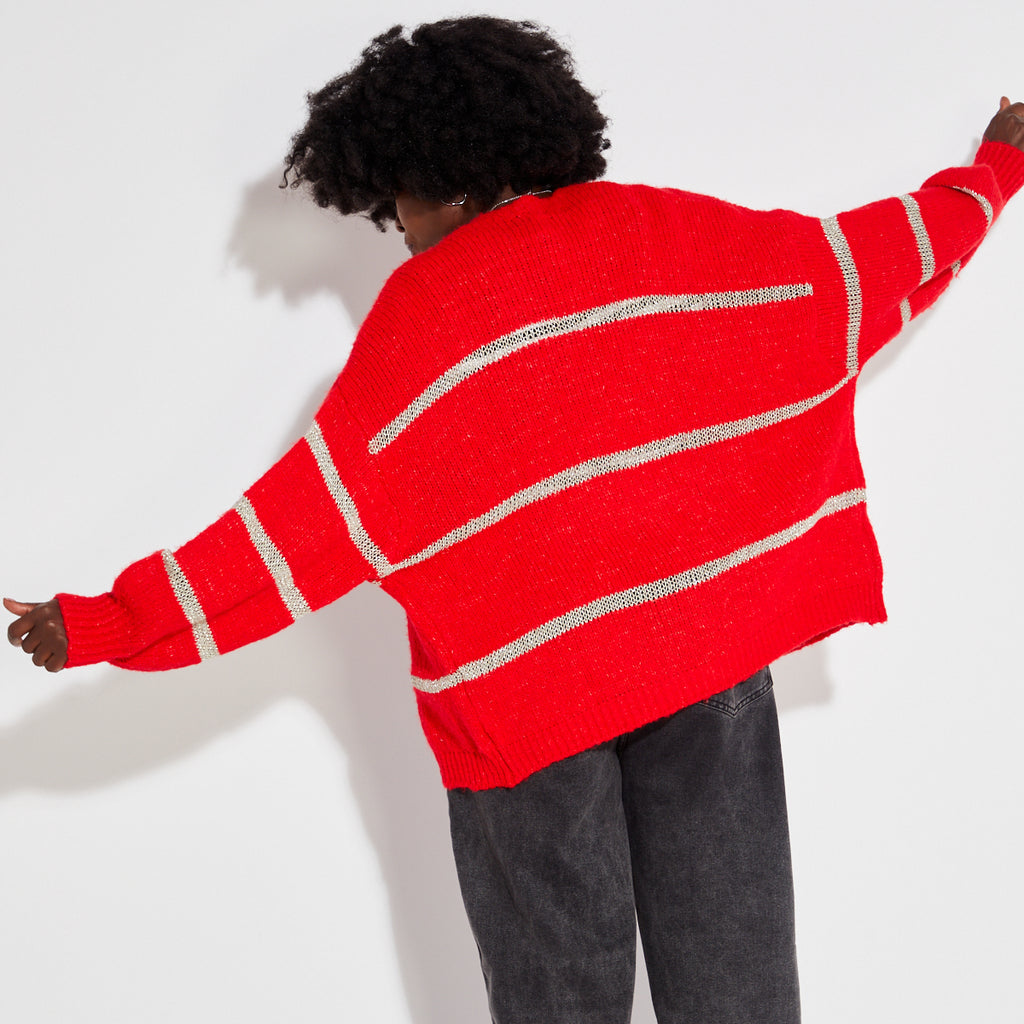 Person wearing a red metallic stripe disco cardigan over a striped shirt on a white background