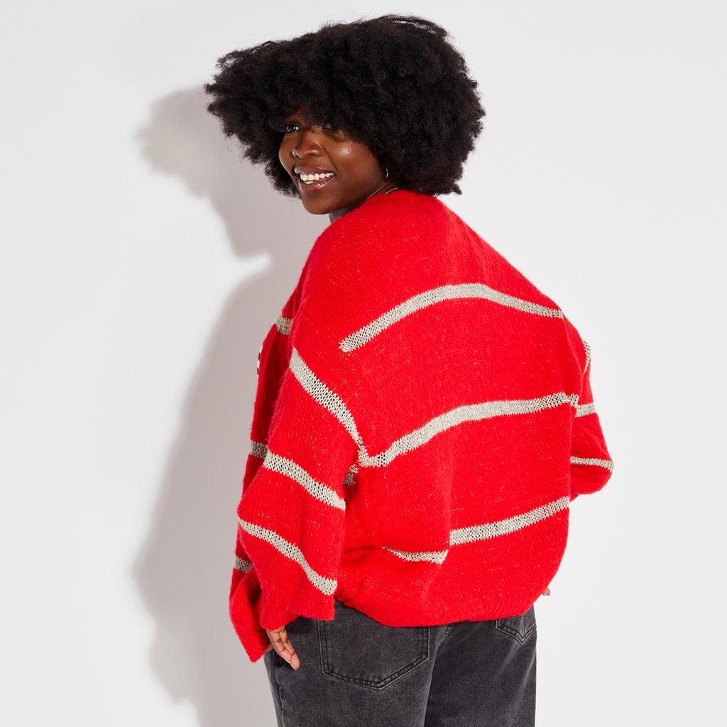Person wearing a red metallic stripe disco cardigan over a striped shirt on a white background