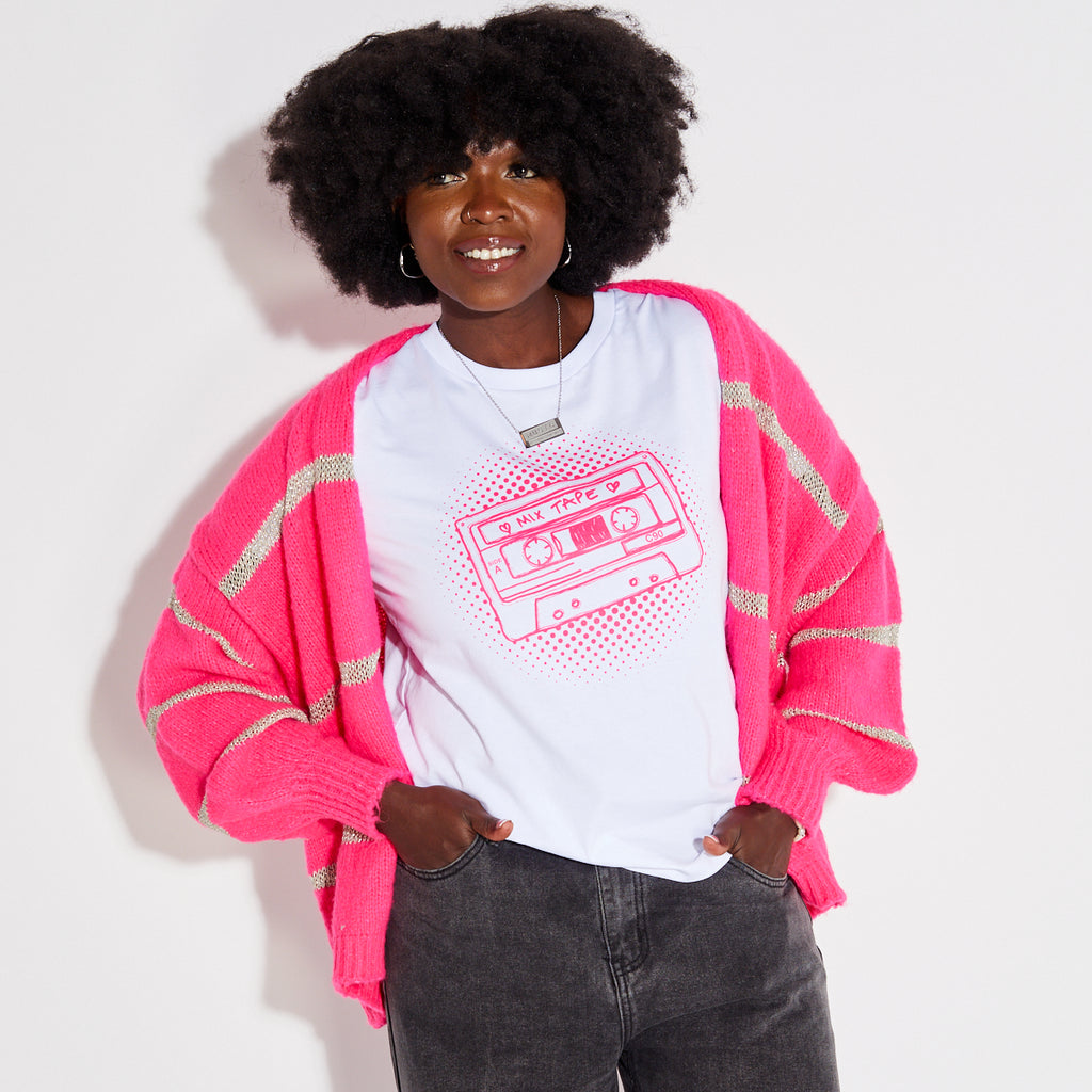 Woman wearing a pink stripe disco cardigan over a white t-shirt with a graphic design on a plain background