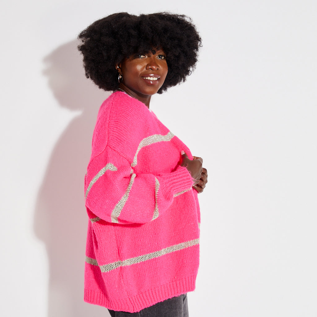 Woman wearing a pink stripe disco cardigan over a white t-shirt with a graphic design on a plain background