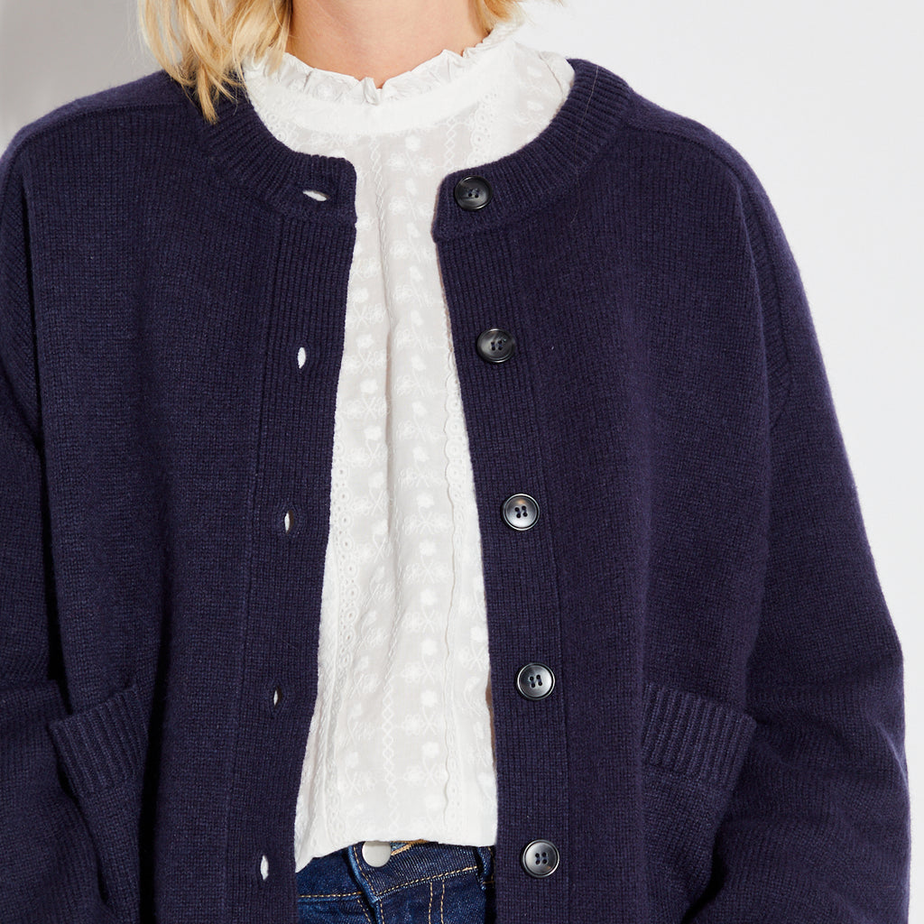 Navy cardigan over a white shirt on a plain background