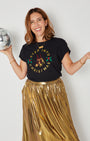 black graphic t-shirt  'STEP INTO CHRISTMAS'  with a gold skirt, holding a silver disco bal