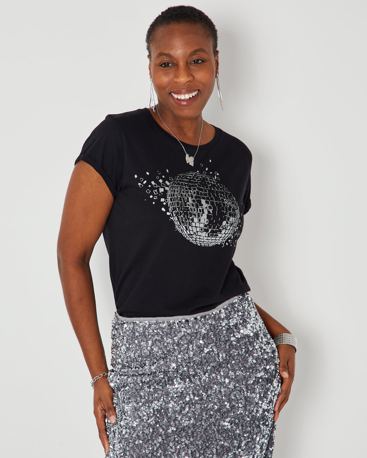 Black short-sleeve t-shirt with a silver disco ball graphic  paired with a silver sequined skirt.