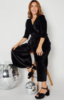 model in Black Rainbow Sparkle Jumpsuit disko kids party collection sitting shot with heels and disco balls
