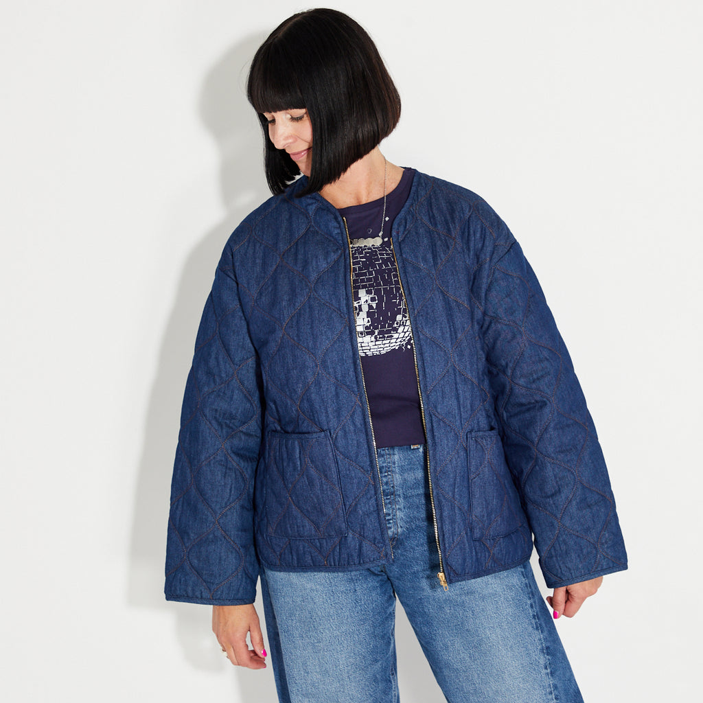 Woman wearing a blue denim quilted jacket on a white background