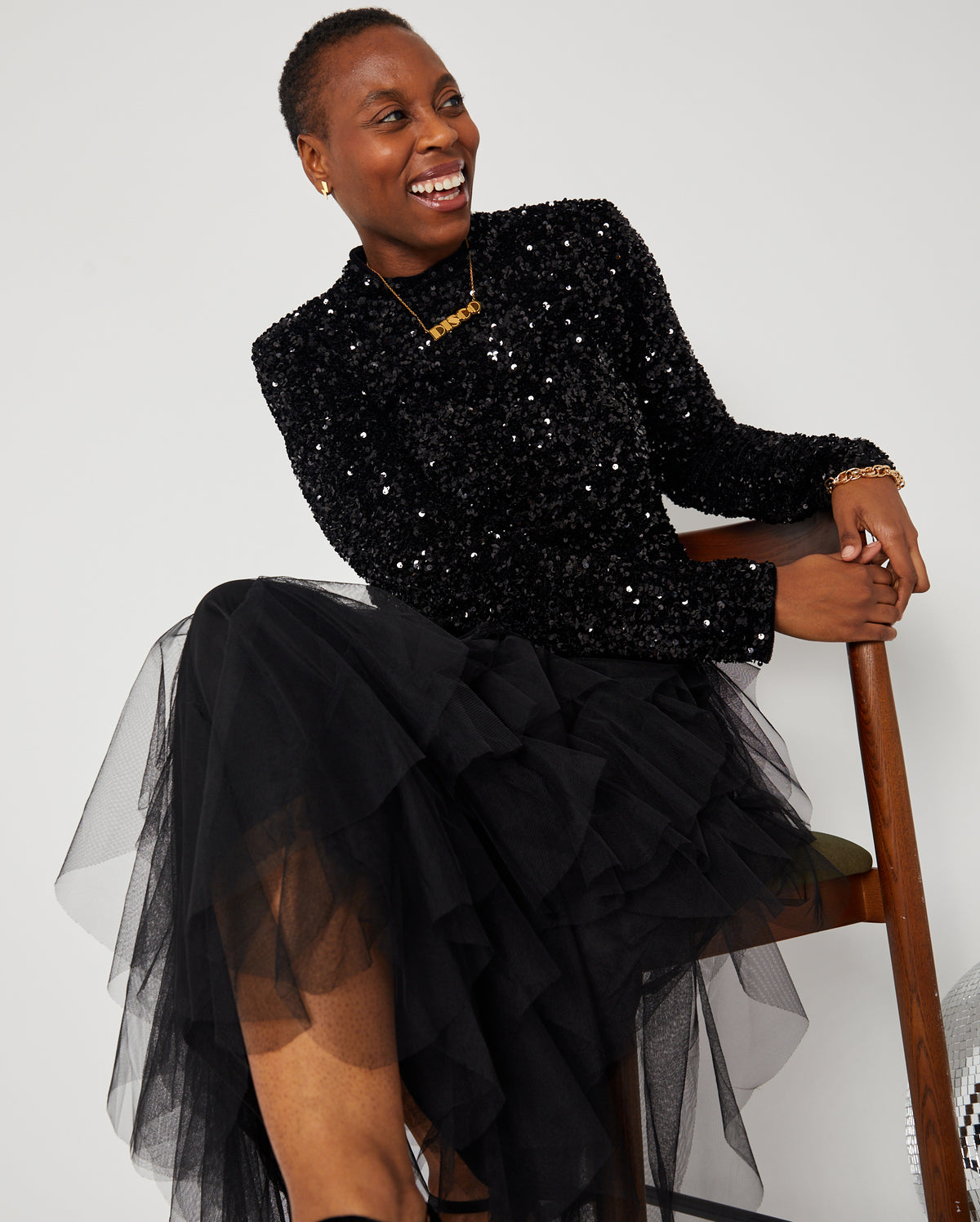 Black Layered Frill Tulle Skirt seated pose with sequin top and gold DISCO pendant