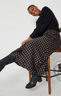 Polka Dot Satin Skirt side view on chair black and gold spots styled with a knit