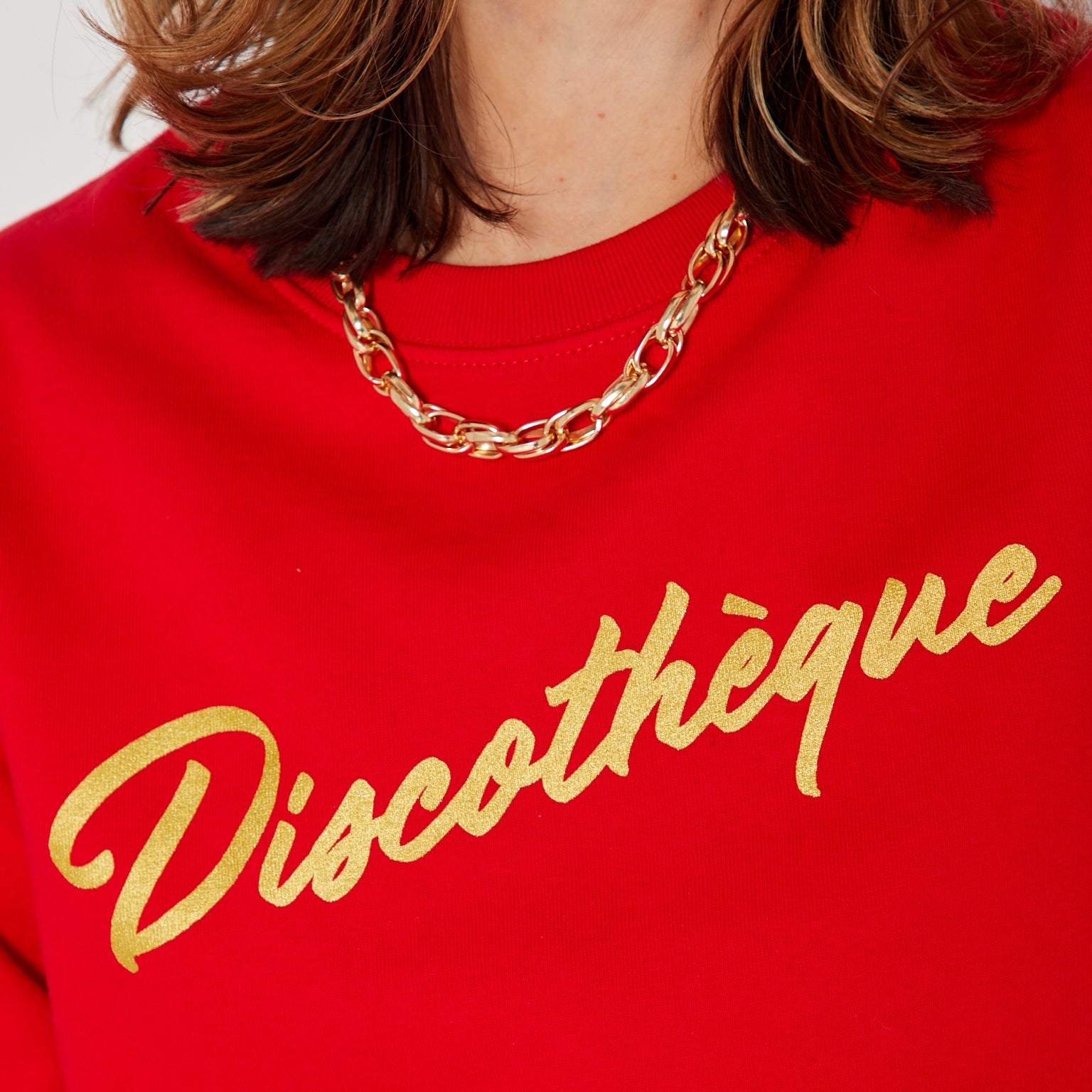 bright red crewneck sweatshirt with 'Discothèque' printed in gold script across the chest,