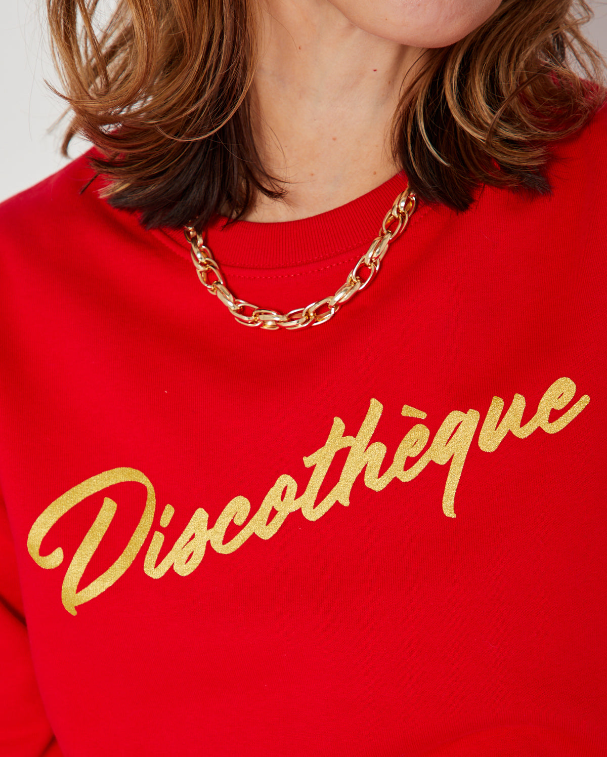 bright red crewneck sweatshirt with 'Discothèque' printed in gold script across the chest,