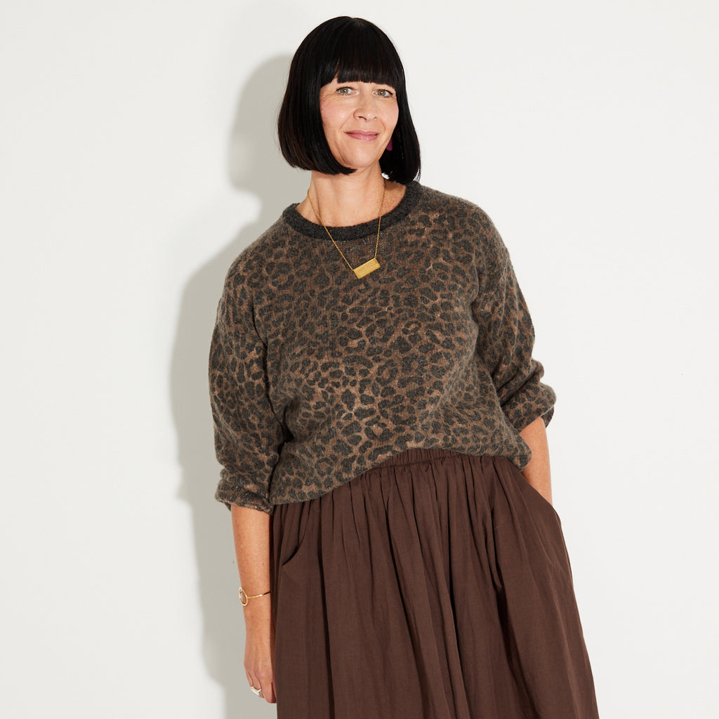 Woman wearing a leopard print sweater and chocolate brown a-libe skirt 