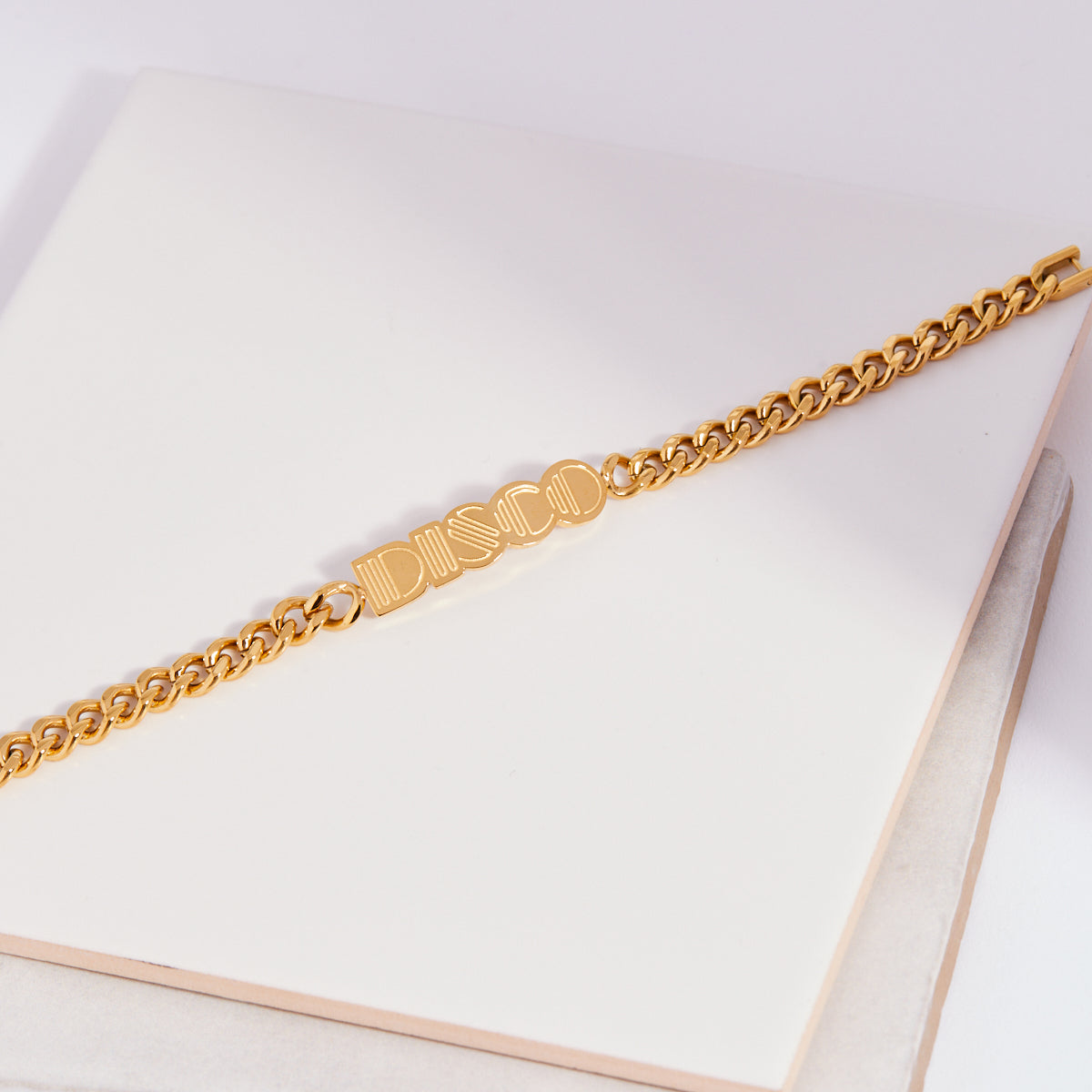 Gold chain DISCO bracelet on a white surface