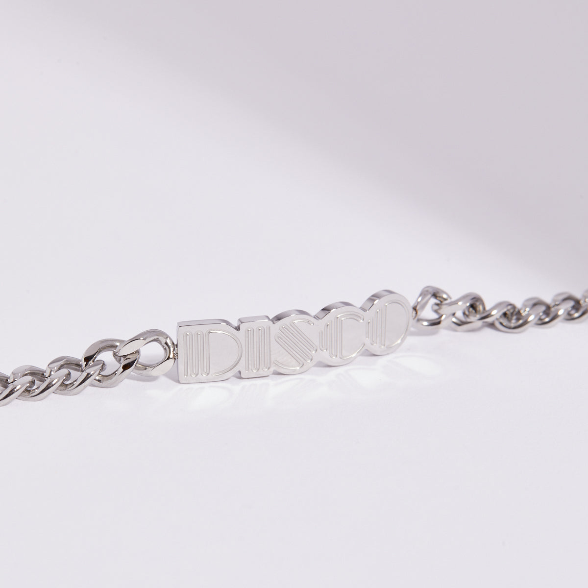 Silver chain bracelet with 'DISCO' engraved on a light gray background