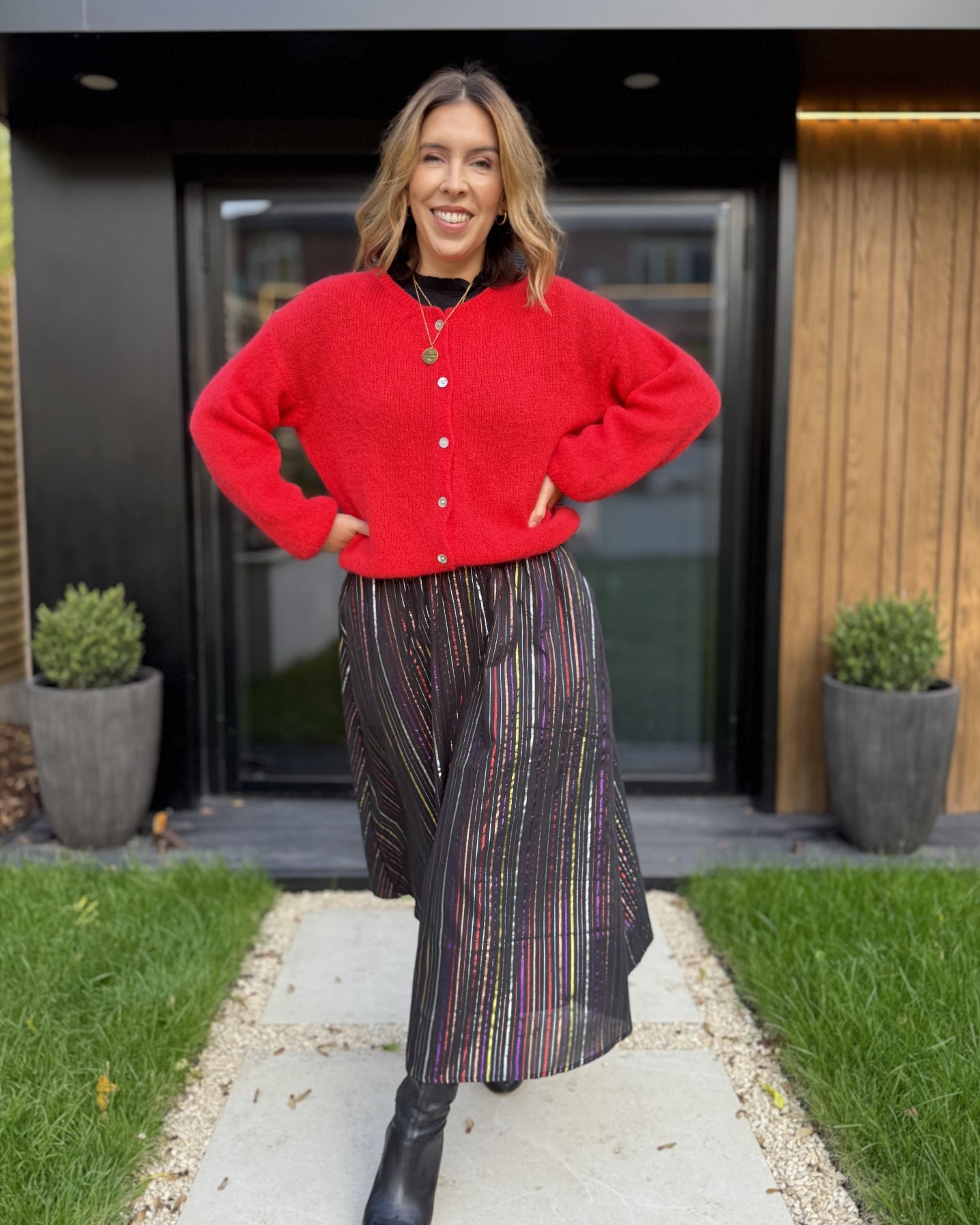 metallic rainbow skirt and red cardigan with black boots