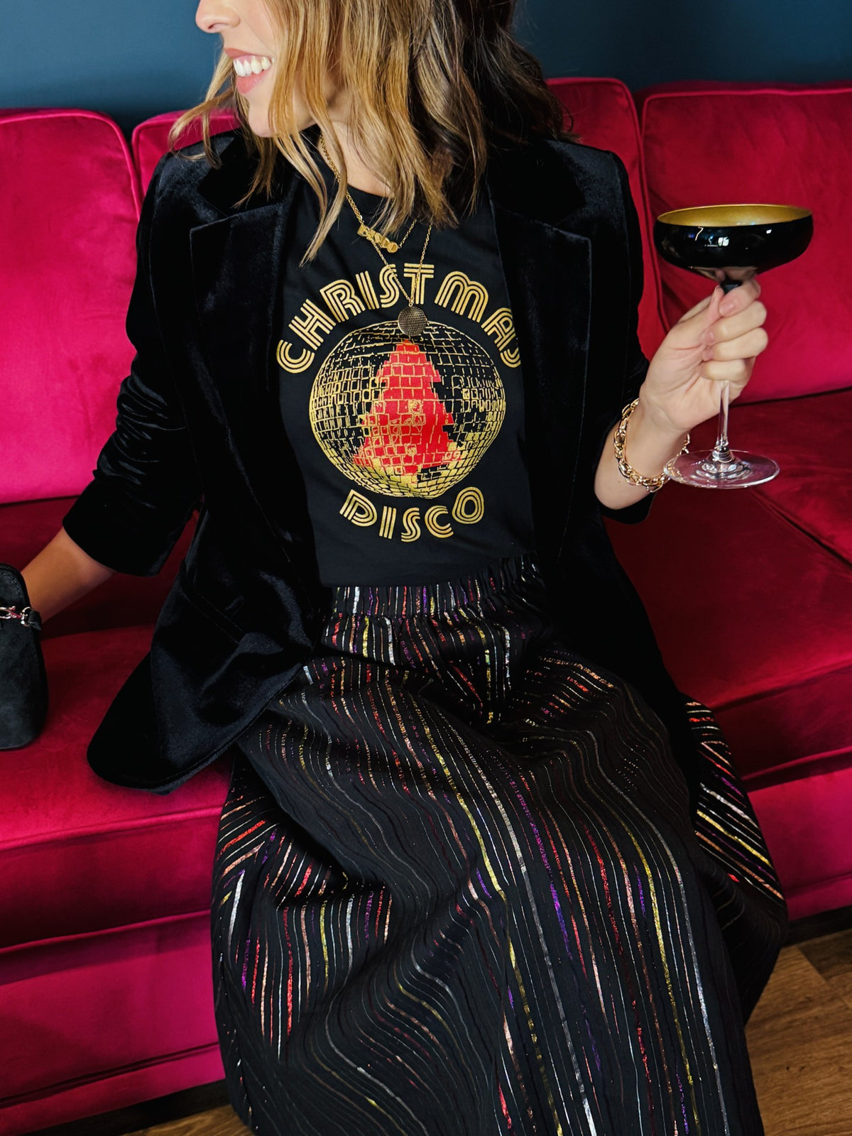 woman in a metallic rainbow skirt and gold metallic and red christmas disco tshirt black 