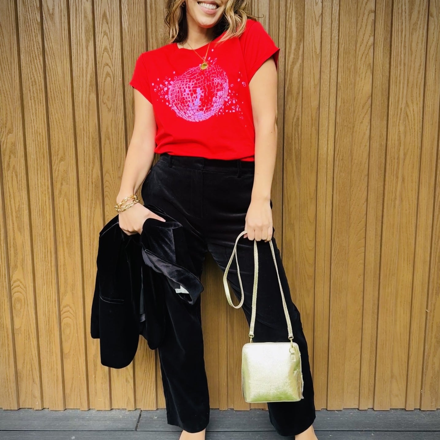 red tshirt with shattered disco ball black trousers and a gold bag for a christmas outfit