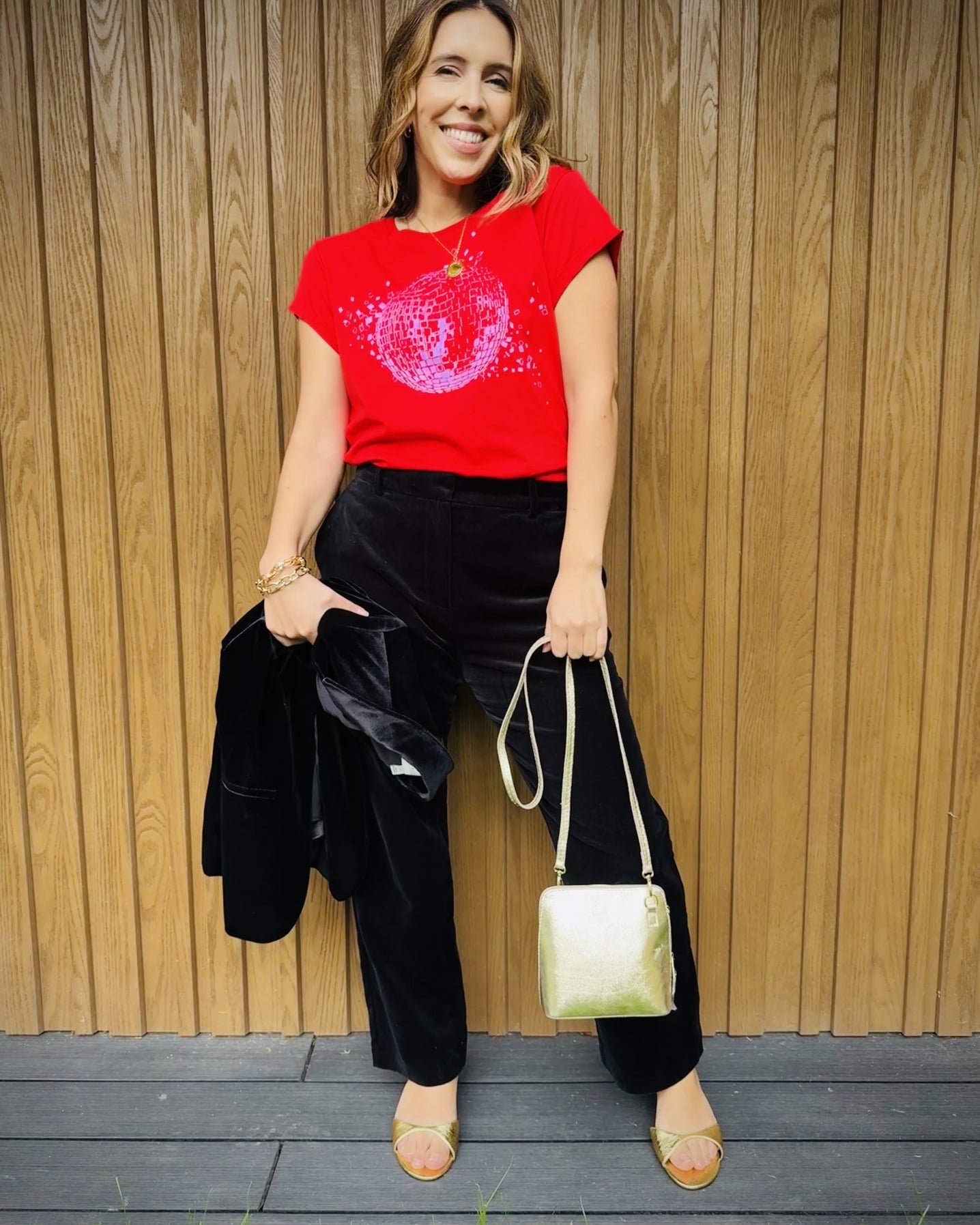 red tshirt with shattered disco ball black trousers and a gold bag for a christmas outfit