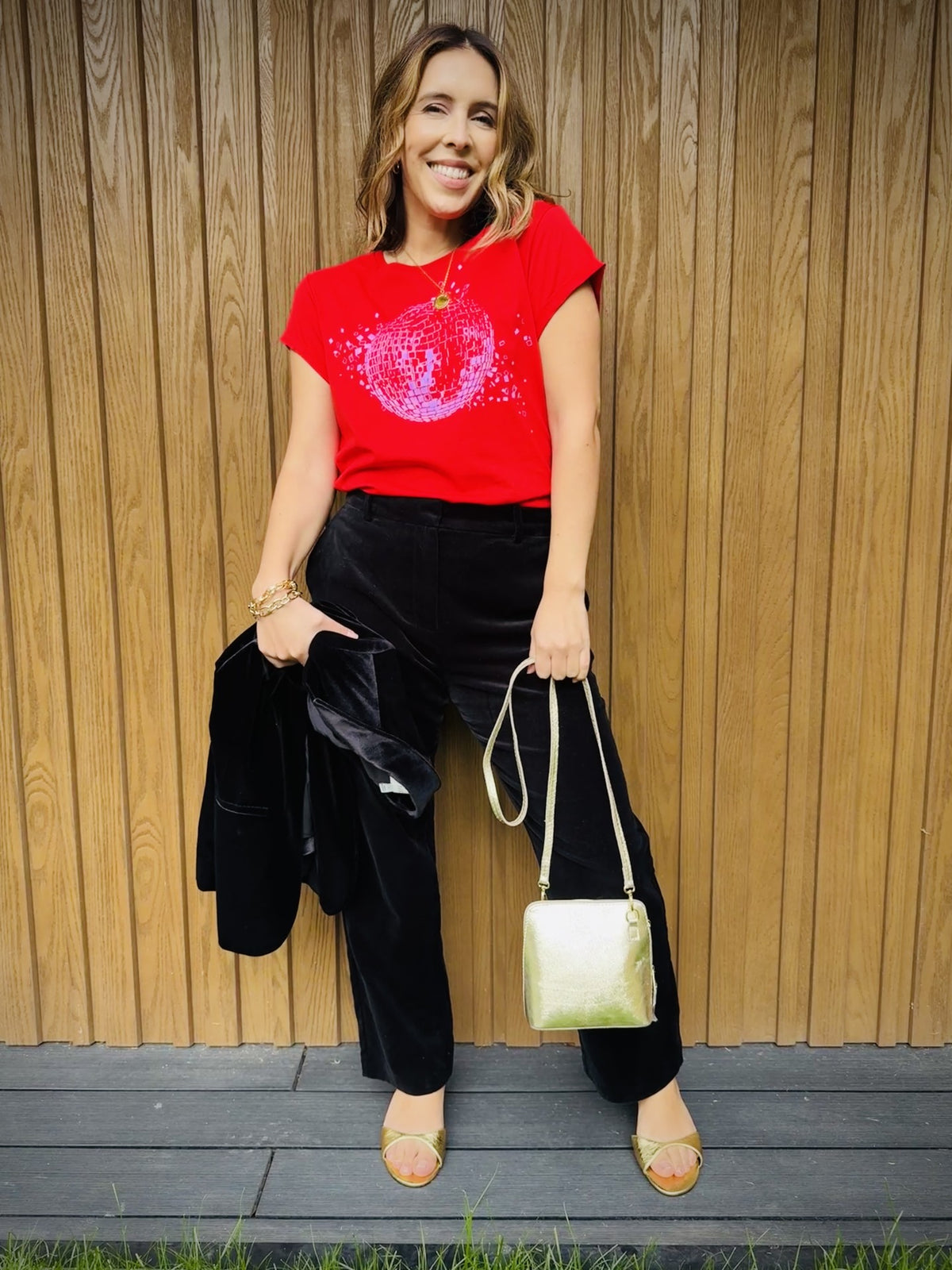 red tshirt with shattered disco ball black trousers and a gold bag for a christmas outfit