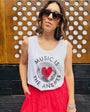 Woman wearing a vest with 'Music is the Answer' text and a red skirt against a wooden background.
