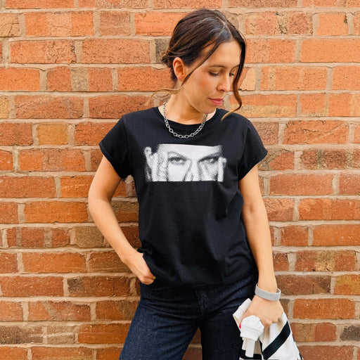 Woman wearing a black t-shirt with white graphic design against a brick wall