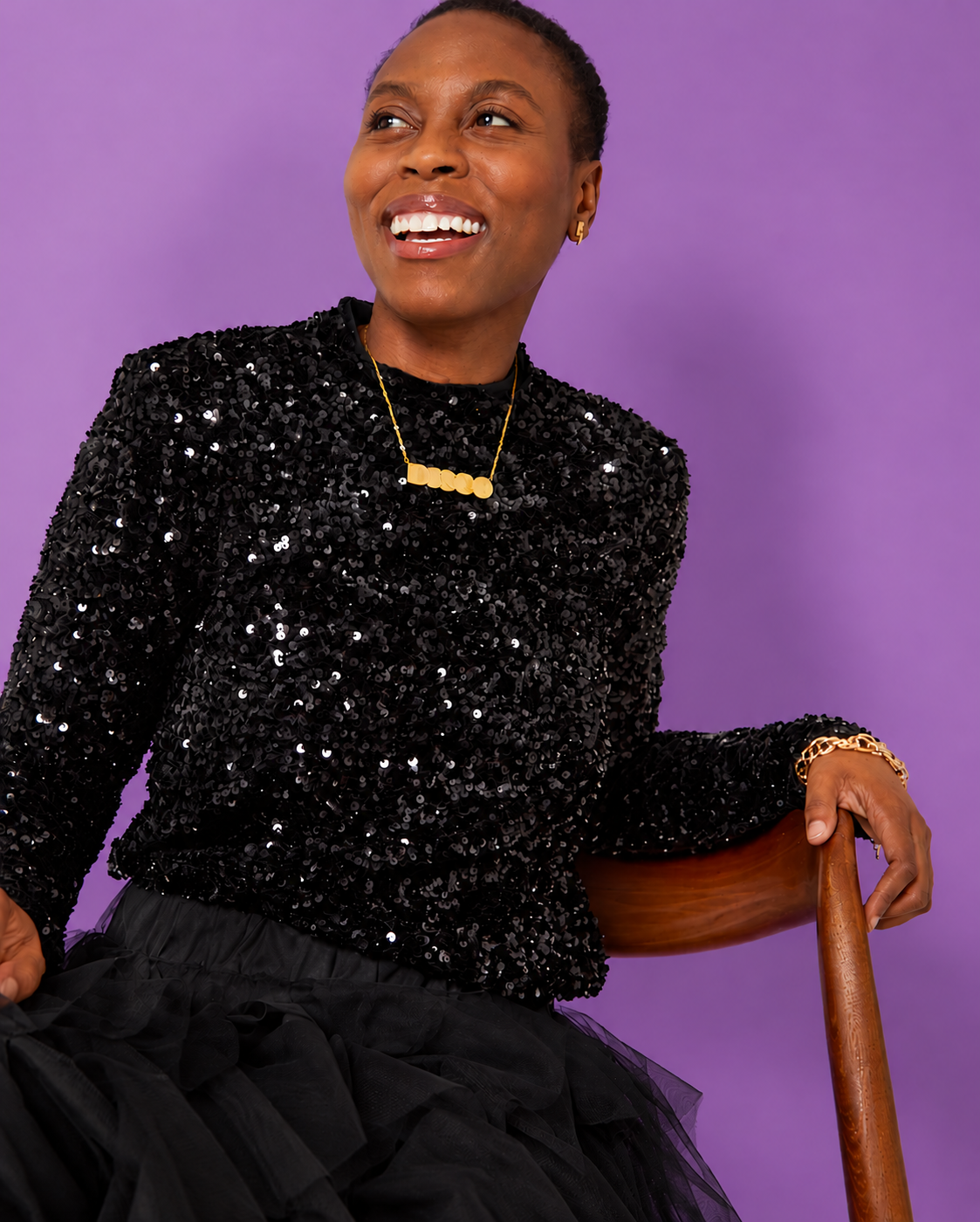 Black Sequin Long Sleeve Top styled with gold DISCO pendant with tulle skirt seated pose