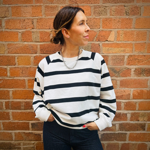 Woman wearing a black and white striped sweater against a brick wall