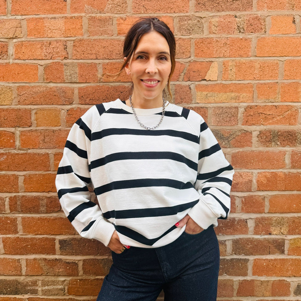 Woman wearing a black and white striped sweater in front of a brick wall