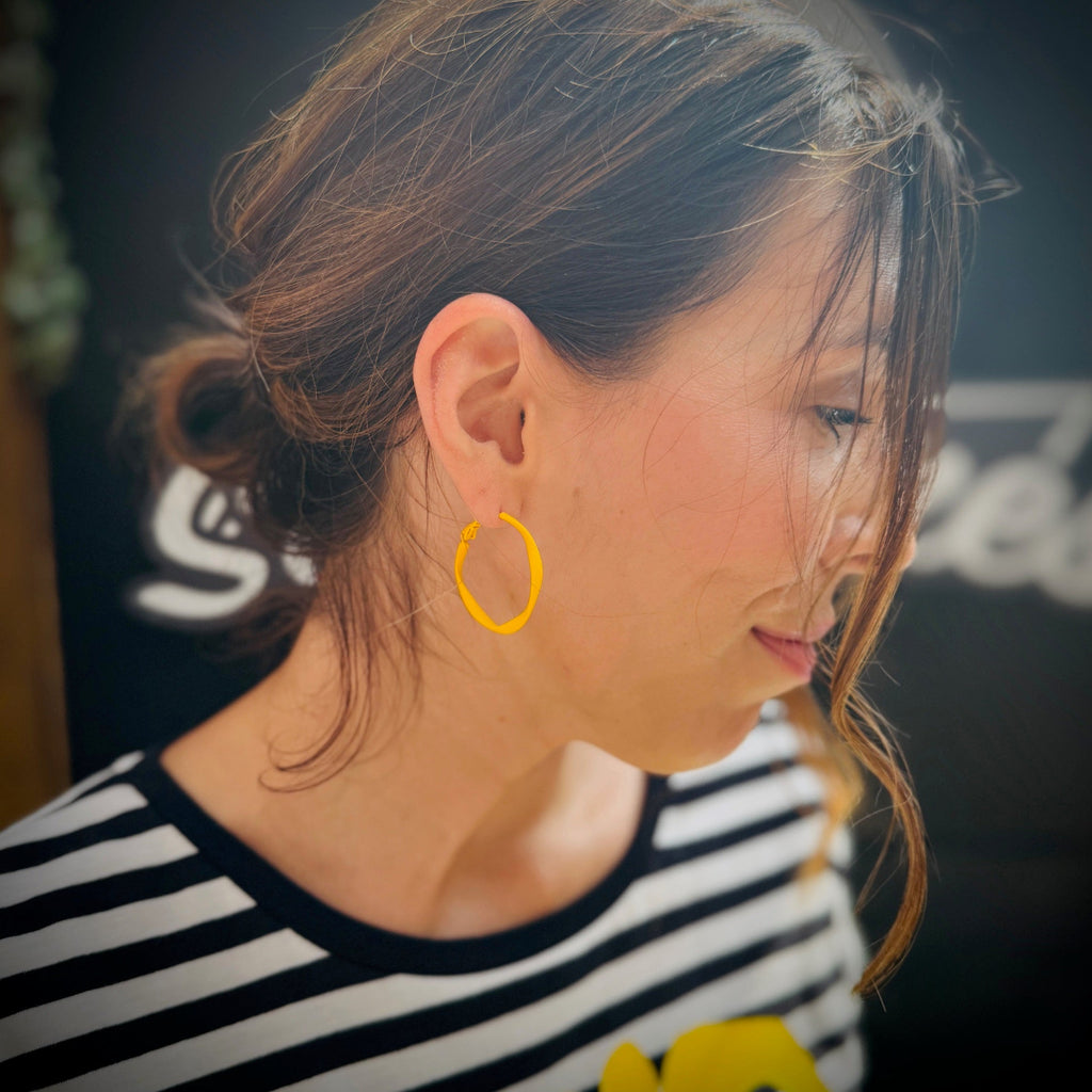 Woman wearing a yellow hoop earring with a blurred background